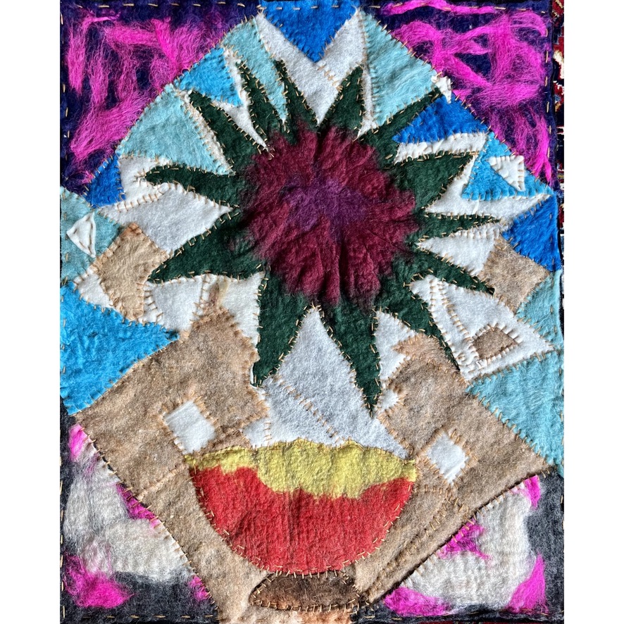 Felt collage featuring a central maroon and green starburst radiating upward from a red and yellow bowl-like form, surrounded by angular patchwork and vibrant magenta and blue fields, evoking a symbolic flower in bloom.