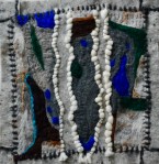 Felt collage with layered grey and stone-toned textures, adorned with three twisted white wool cords running vertically across a terrain of deep green, blue, and earthy brown patches — evoking a woven landscape or ancient pathway.