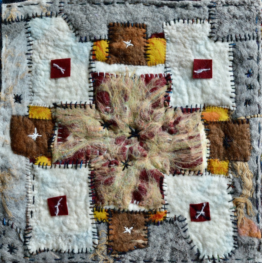 Textured felt artwork with earthy patchwork in brown, yellow, and grey, featuring a central fuzzy red starburst and embroidered white crosses, reflecting layered memory.