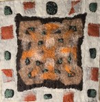 Earthy-toned felt collage with a rust and brown patterned center surrounded by stitched pale fabric squares and a dark green ceramic element at the top — blending textile warmth with sculptural accent.
