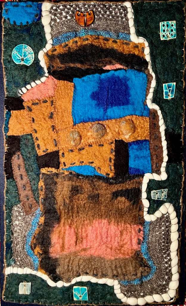Vertical felt collage with layered ochre, blue, and brown sections, stitched detailing, and ceramic tile accents, evoking nomadic architecture and textile memory.