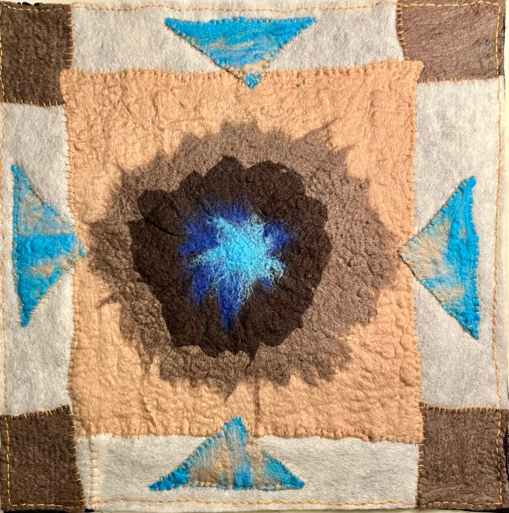 Textile collage in wool featuring a radiant blue core at the center, surrounded by earthy tones and framed with stitched geometric motifs in brown, cream, and vibrant turquoise. Four triangle forms evoke directional movement, giving the piece a sense of sacred symmetry and gentle protection.